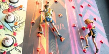 Ein Junge und ein Mädchen klettern an einer Kletterwand in der Play Indoor Spielwelt Serfaus