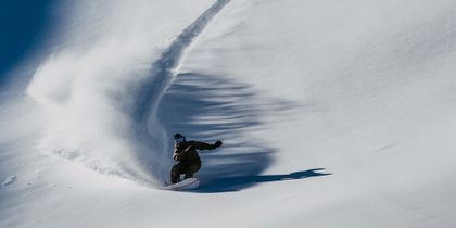 Mark Morris hinterlässt eine tiefe Spur im Powder auf einem Burton Snowbaord in einem Tiefschnee Berghang