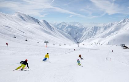 Eine Familie fährt auf Ski eine Piste an einem sonnigen Wintertag im Skigebiet von Serfaus-Fiss-Ladis hinunter