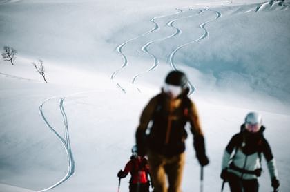 Finde alles für dein nächstes Abenteuer in den Bergen bei Patscheider Sport Eine Gruppe von Tourengehern gehen mit den Tourenski den Berg hinauf. Im Hintergrund sind Spuren im Tiefschnee