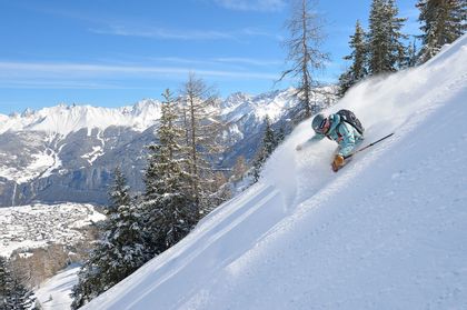Ein Freerider fährt im tiefen Pulverschnee einen steilen Hang im Skigebiet in Fiss hinunter