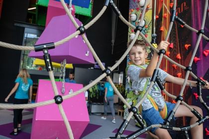 Ein Junge klettert an einem Netz in der Play Indoor Spielwelt Serfaus