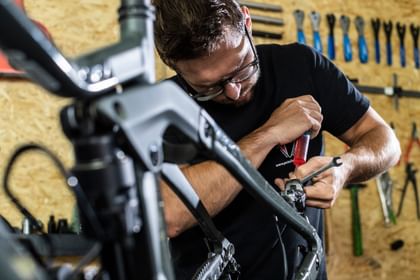 Ein Mitarbeiter macht einen Fahrradservice an einem Mountainbike in der Werkstatt