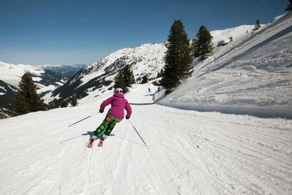 Eine Skifahrerin fährt auf einer Piste in der Berglandschaft von Serfaus mit den Againern ski