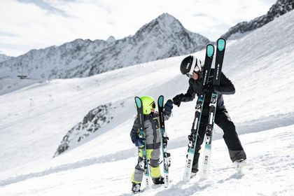 Eine Mutter und ein Kind stehen mit ihren Ski auf der Piste im Skigebiet und geben sich eine High-Five