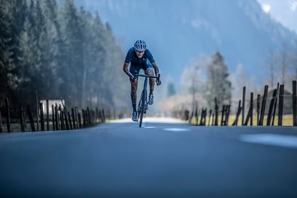 Ein Mann fährt auf einem Scott Addict Gravelbike Straße entlang im Hintergrund ist ein e Berglandschaft