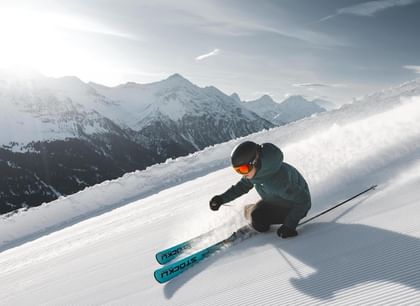 Lässige Schwünge auf und abseits der Piste mit Patscheider Sport Eine Skifahrerin carved mit einem Ski der Marke Stöckli auf einer frisch präparierten Skipiste.