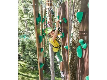 Ein Junge klettert an der Kletterwand im Waldseilpark X-Trees Serfaus