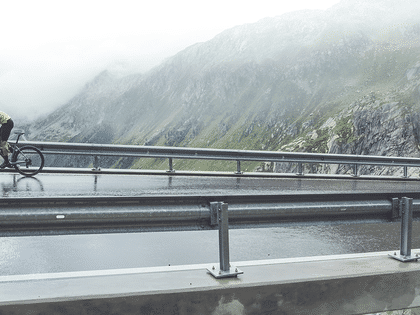 Ein Mann fährt auf einem Scott Addict Gravelbike Straße entlang im Hintergrund ist eine Berglandschaft