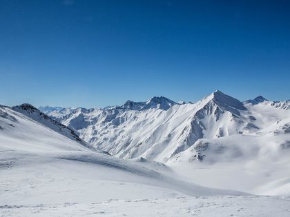 Winterliches Bergpanorama mit tief verschneiten Berghängen und Gipfeln und blauem Himmel im Skigebiet Serfaus-Fiss-Ladis 