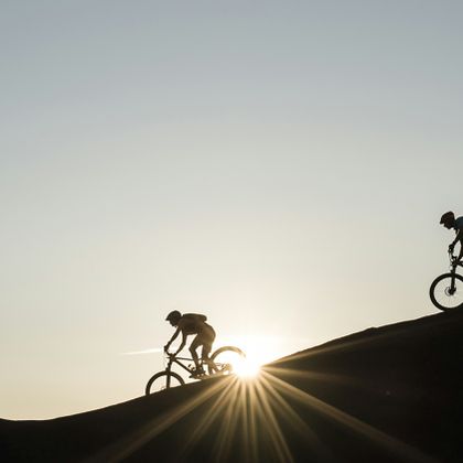 Eine Gruppe fährt auf Scott Mountainbikes einen Berggrat entlang im Sonnenuntergang