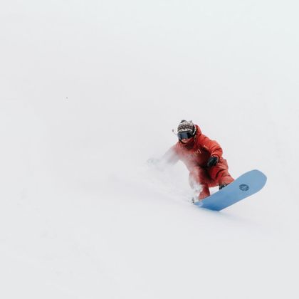 Ein Snowboarder fährt mit einem Family Tree Board von Burton durch tiefen Powder Tiefschnee