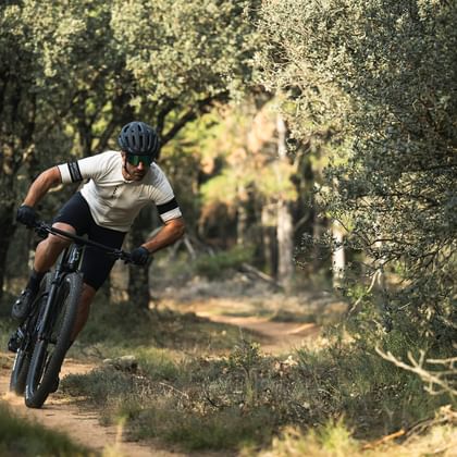 Ein Mann fährt auf seinem Mountainbike einen Trail im Wald hinunter.