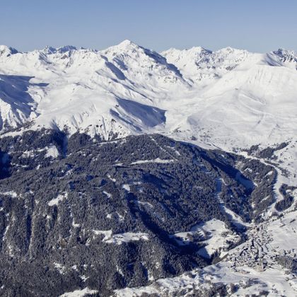 Luftaufnahme von Serfaus im Winter mit dem Alpkopf im Vordergrund und dem Skigebiet von Serfaus Plansegg und Königsleithe im Hintergrund