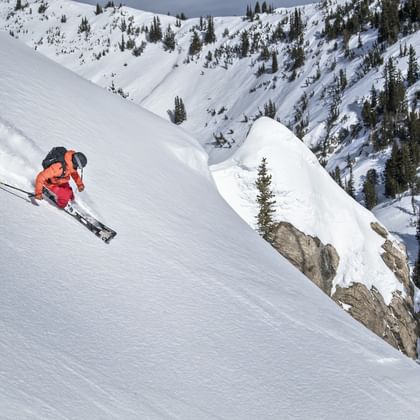 Eine Skifahrerin fährt mit Scott Ski im tiefen Pulverschnee einen steilen Berg hinab