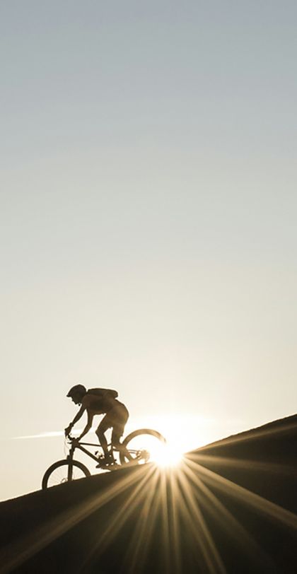 Eine Gruppe fährt auf Scott Mountainbikes einen Berggrat entlang im Sonnenuntergang
